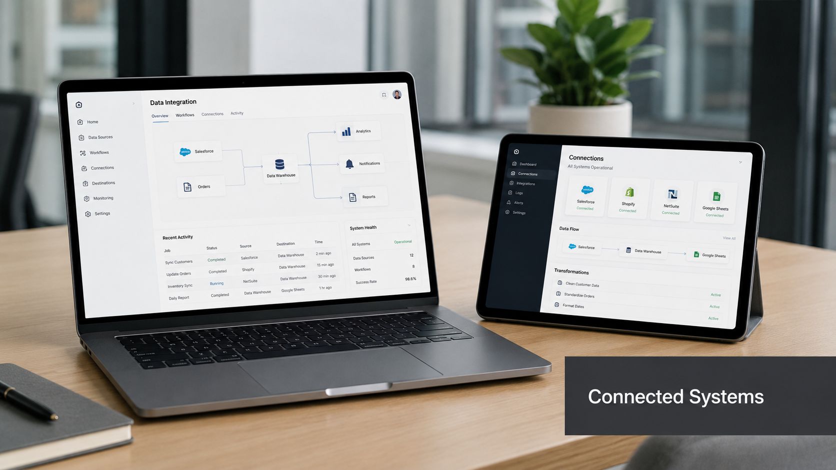 A modern laptop and tablet displaying data integration and system connection dashboards on a wooden office desk.